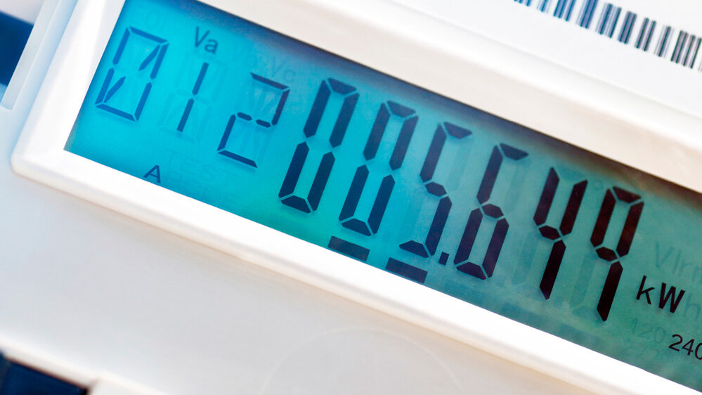 Ein moderner Stromzähler mit einer blauen Hintergrundbeleuchtung zeigt den Verbrauch an.