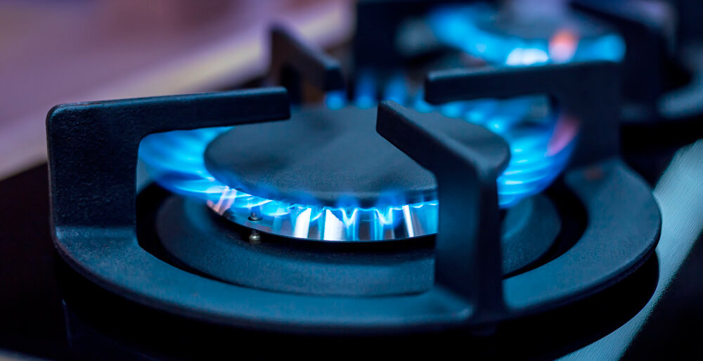 Eine Gasflamme leuchtet hellblau auf einem modernen Kochfeld, bereit zum Kochen.